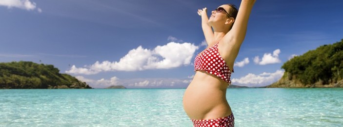 pregnant woman with her arms outstretched at the Caribbean beach