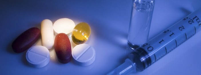 Various pills next to a syringe